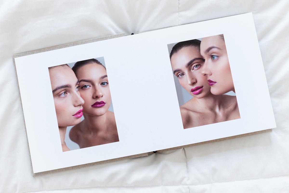 Artifact Uprising Layflat Photo Album opened to two-page spread with portrait of two women on one page and nearly identical photo mirrored on right page