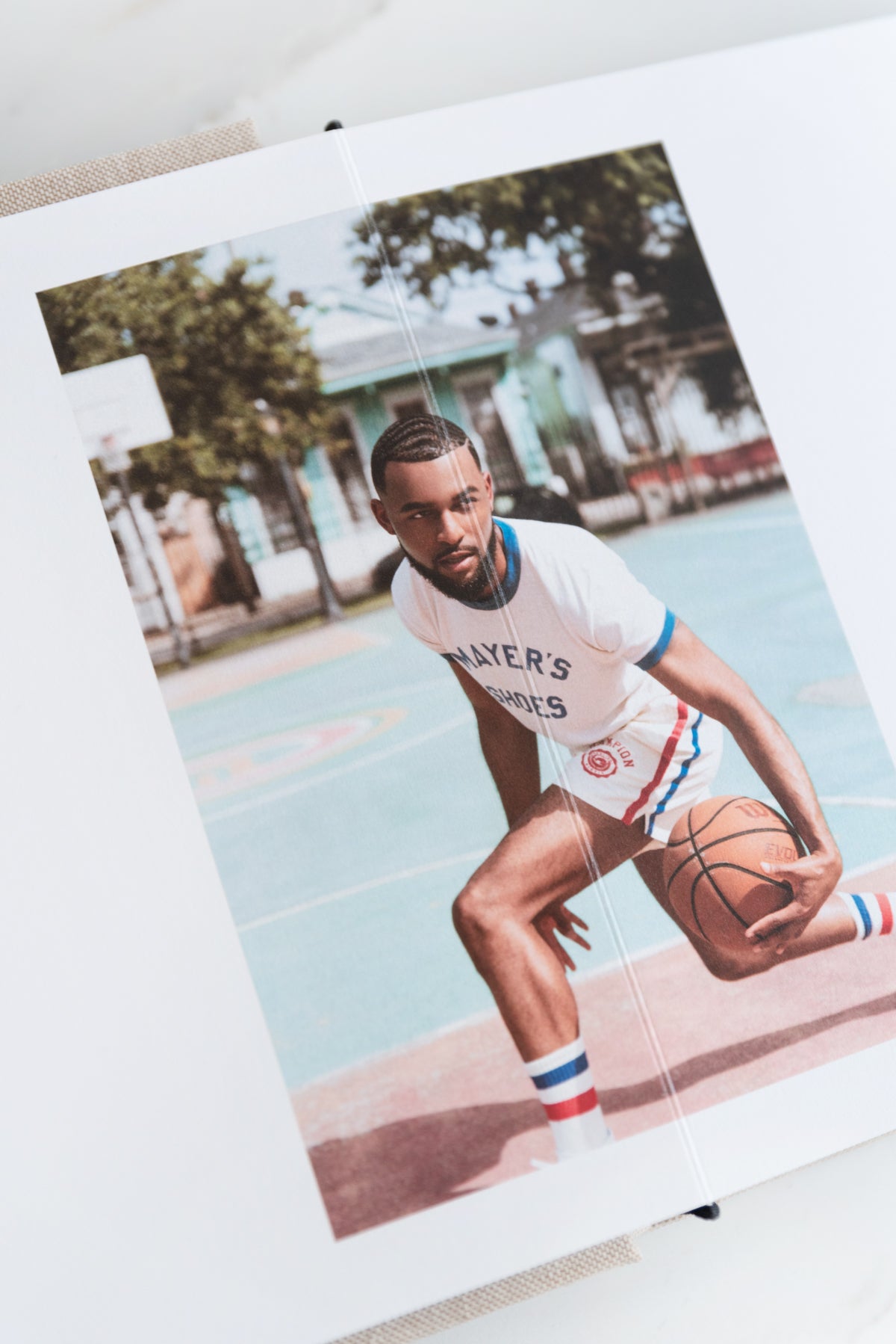 Artifact Uprising Layflat Photo Portfolio Book opened to mid-motion portrait of young man dribbling basketball between his legs