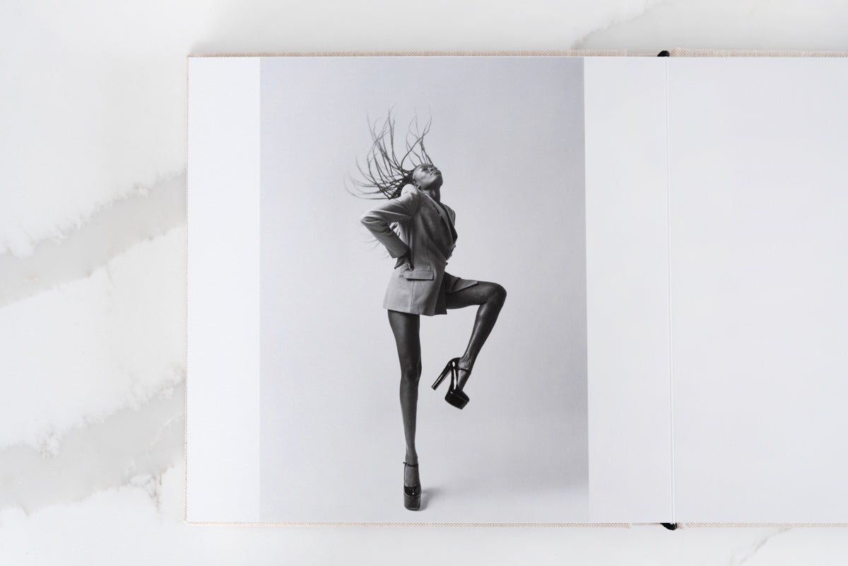 Artifact Uprising Layflat Photo Portfolio Book opened to mid-motion portrait of woman in platform heels flipping hair back