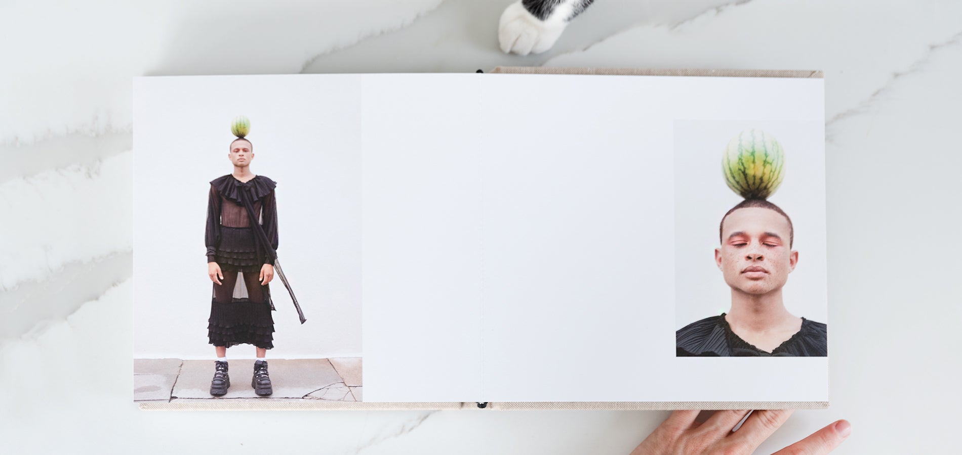 Artifact Uprising Layflat Photo Album opened to two page spread with high-fashion portrait of man balancing watermelon on his head on either page