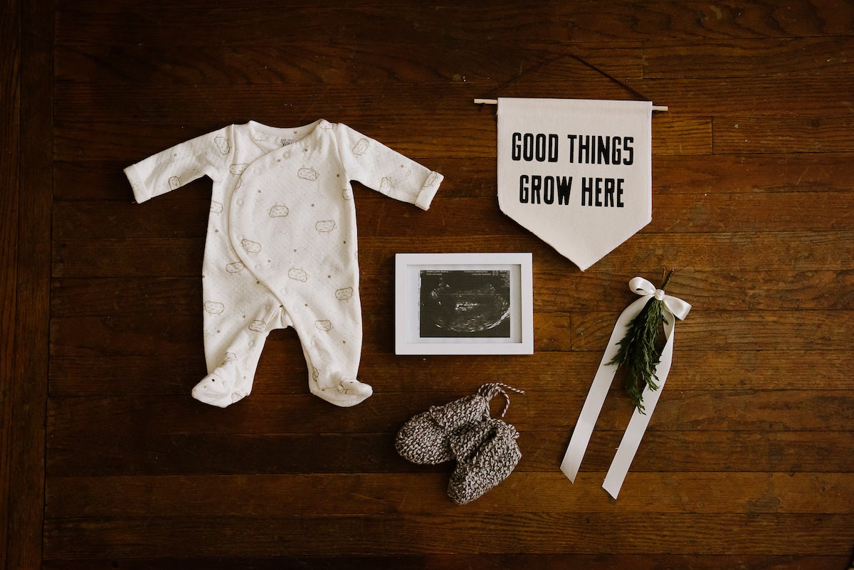 Framed sonogram laid out next to baby garments and nursery decor items