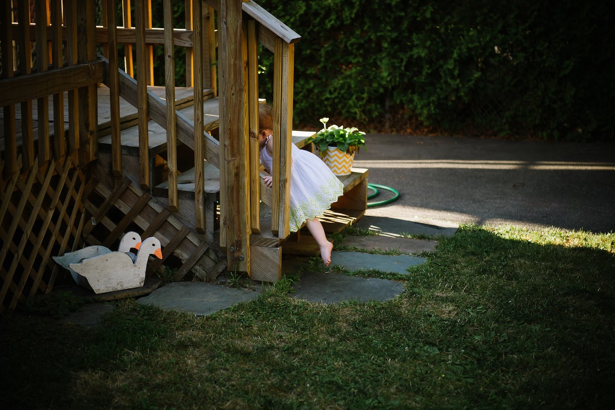 Little girl climbing up wooden patio stairs