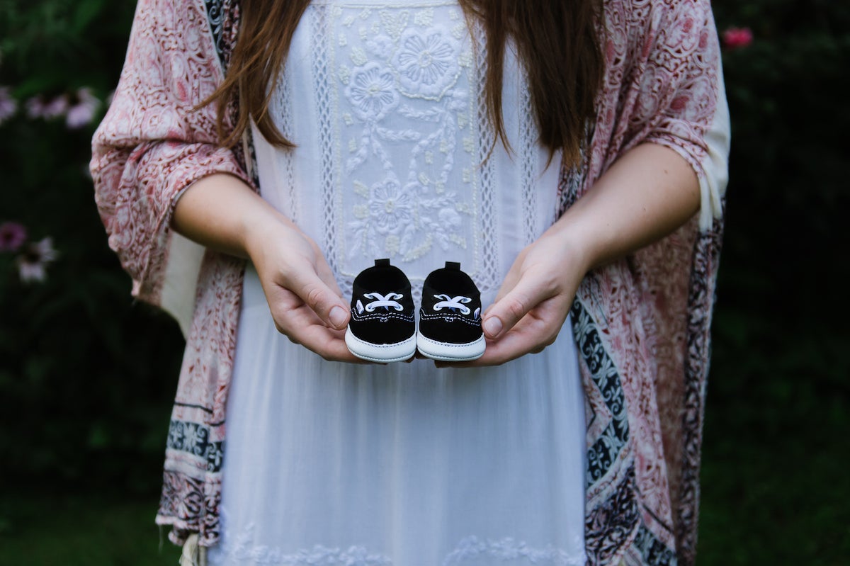 Photo by Martha Swann-Quinn of woman's hands holding up baby shoes