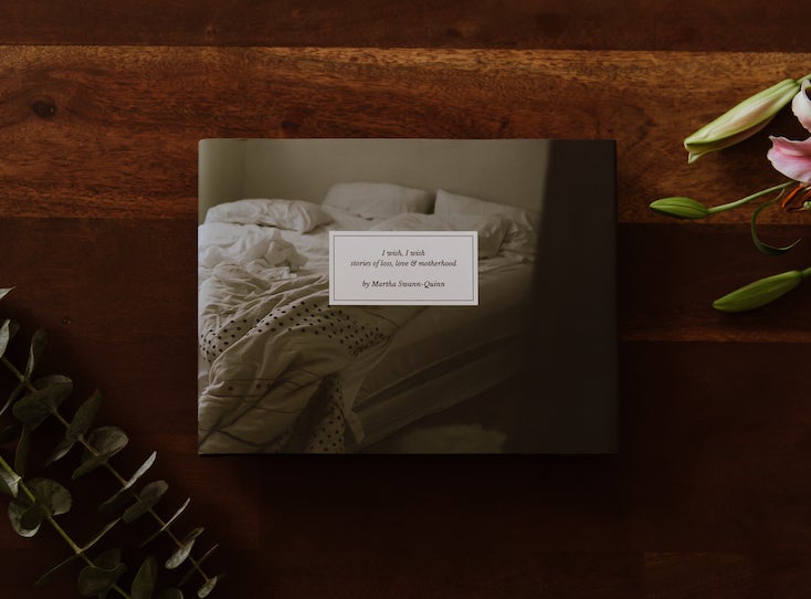 Photo by Martha Swann-Quinn of Artifact Uprising Hardcover Photo Book on wooden surface with pink lilies and eucalyptus