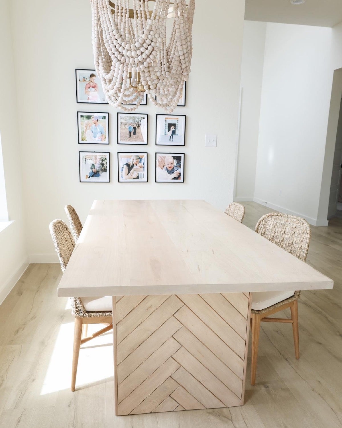 9 frame grid gallery wall in minimalist dining room featuring family portraits in Artifact Uprising Modern Metal Frames behind dining table and roped chandelier