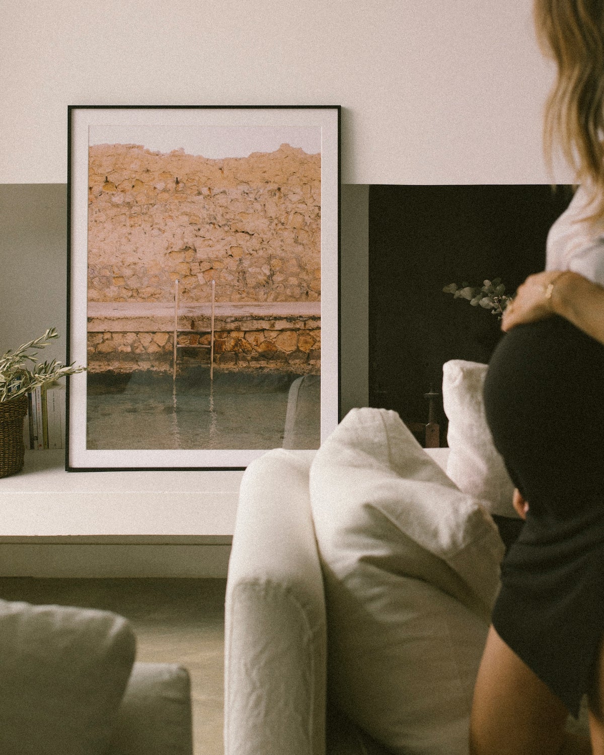 Pregant woman holding belly as she looks at large Artifact Uprising Modern Metal Frame placed on mantel next to fireplace