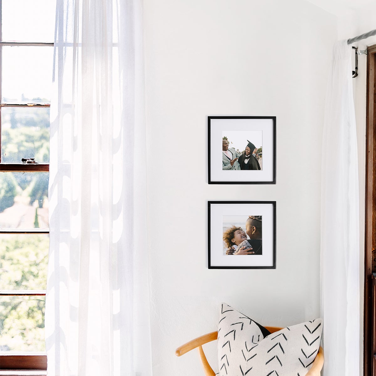 Family photos featured in two Artifact Uprising Metal Tabletop Frames in Black hung vertically in corner of room alongside window frame
