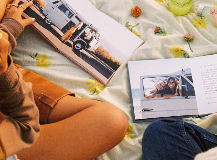 Two friends flipping through identical Artifact Uprising Everyday Photo Books featuring photos of a trip together