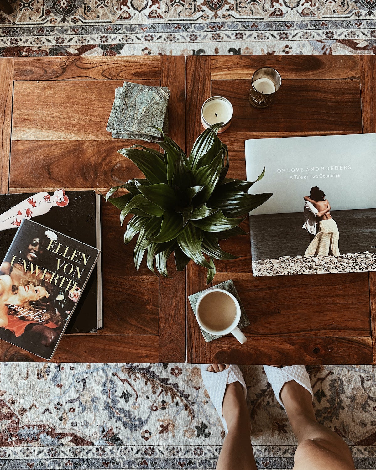 Artifact Uprising Hardcover Photo Book titled Of Love & Borders on coffee table next to other books.