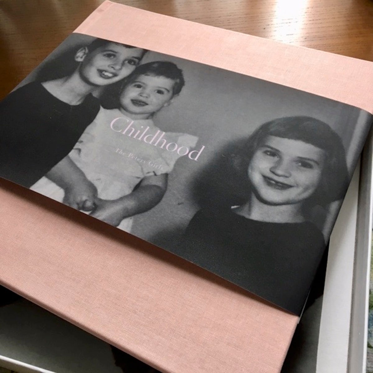 Artifact Uprising Hardcover Photo Book titled Childhood featuring black and white cover photo with three siblings together