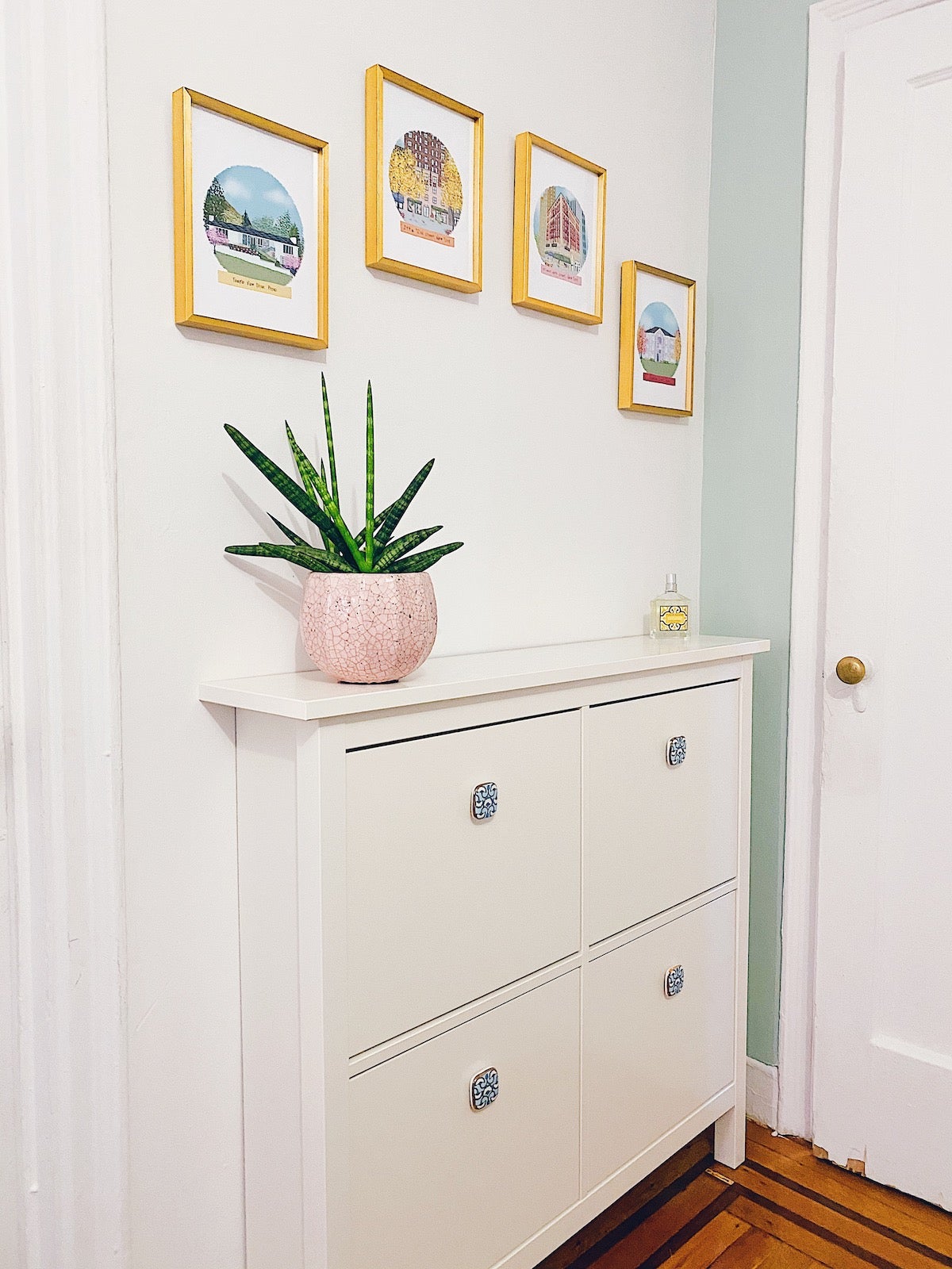 Four frames in an arch over a dresser with drawn portraits of homes