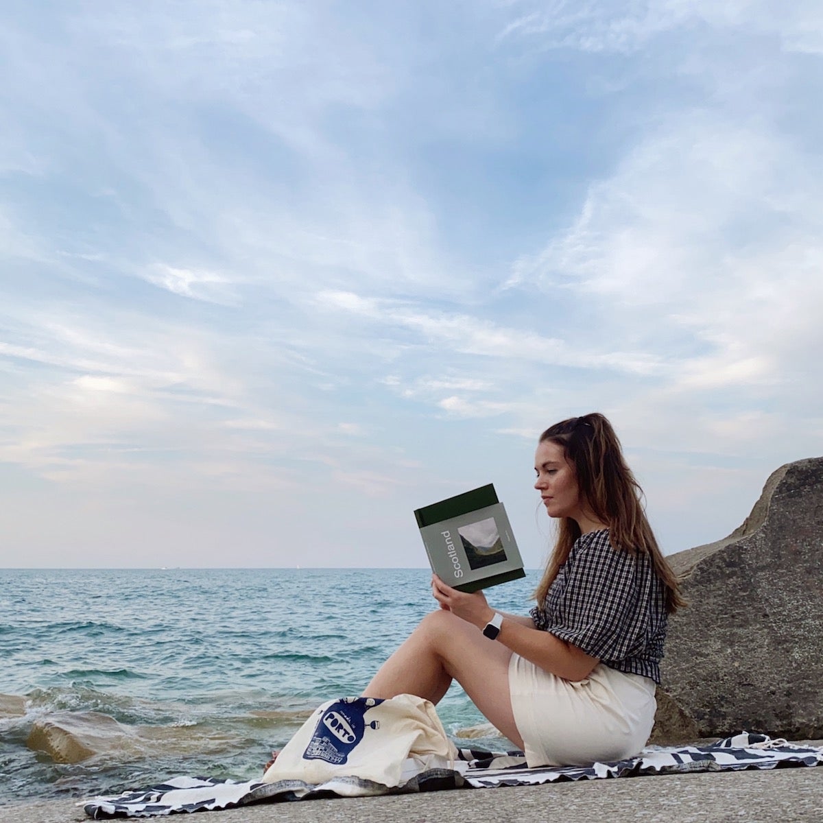 Woman sitting on the beach looking at her travel photo book