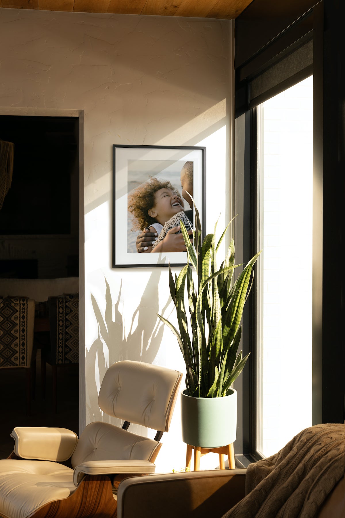 Artifact Uprising Modern Metal Frame in Black featuring photo of young siblings embracing is hung in corner of rooom behind snake plant