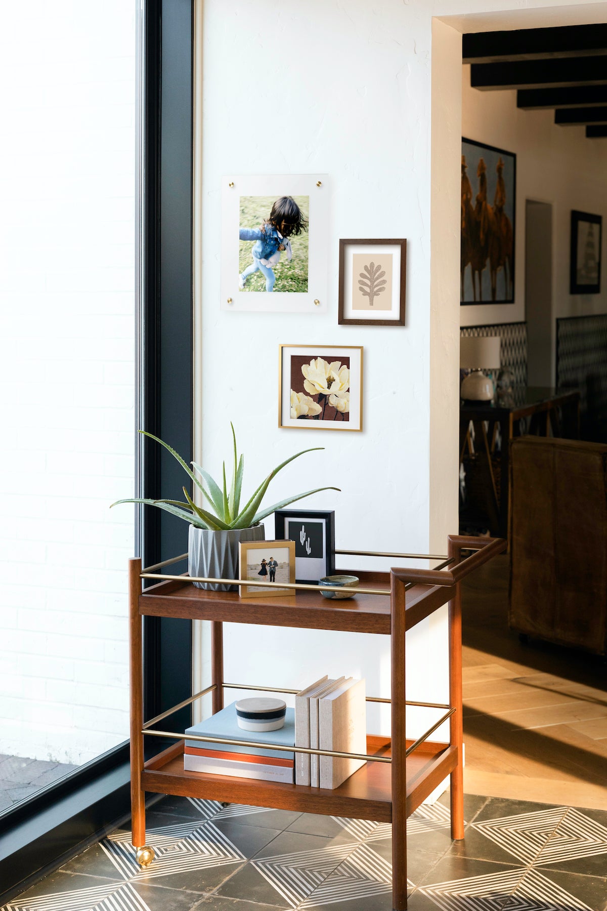 A corner filled with frames, a side table, photo books, and greenery.