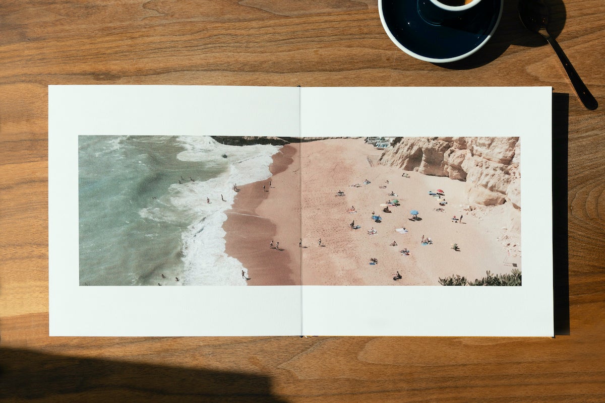 Artifact Uprising Layflat Photo Album opened to two-page image of a beach taken from overhead