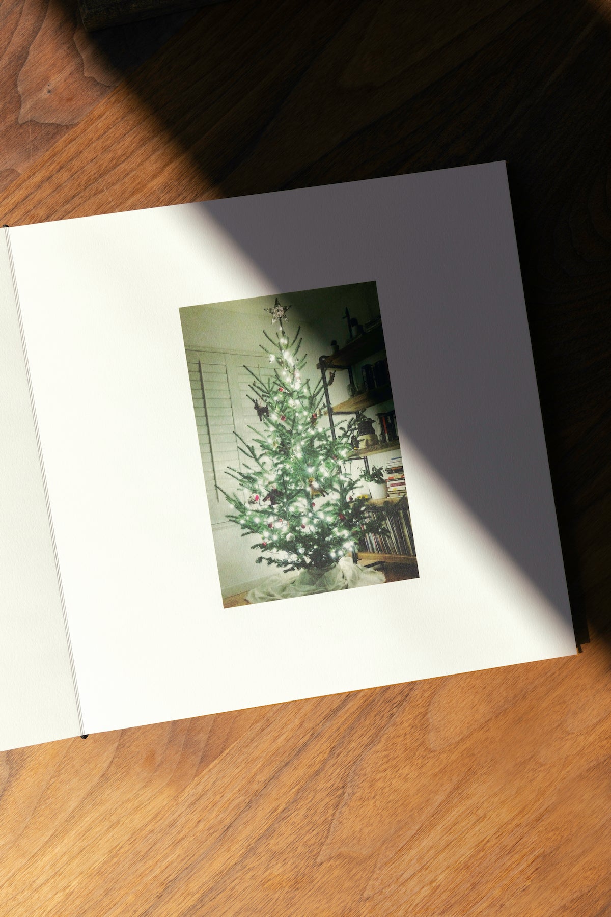 Artifact Uprising Layflat Photo Album opened to photo of brightly lit Christmas tree