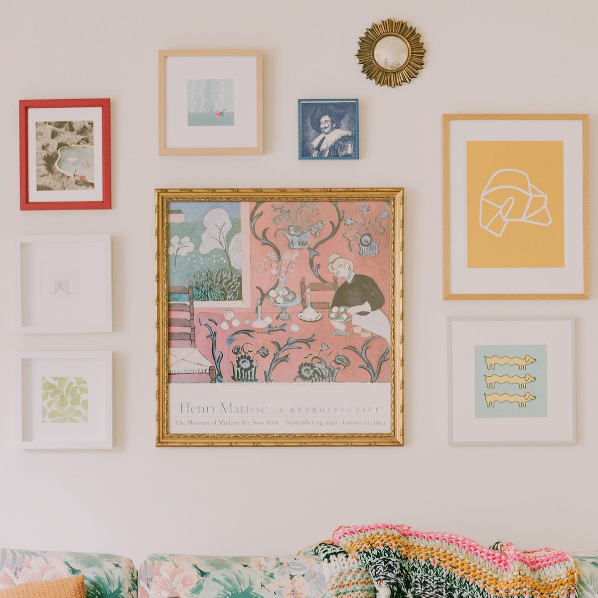 A colorful, pastel couch with an equally colorful gallery wall above — filled with art prints and photos.