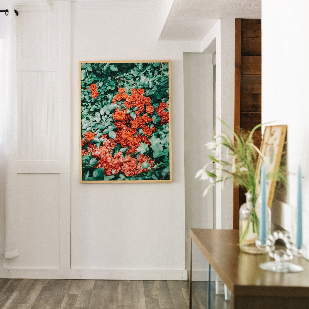 A living room scene where one wall has an oversized frame with a photo of bright red flowers.