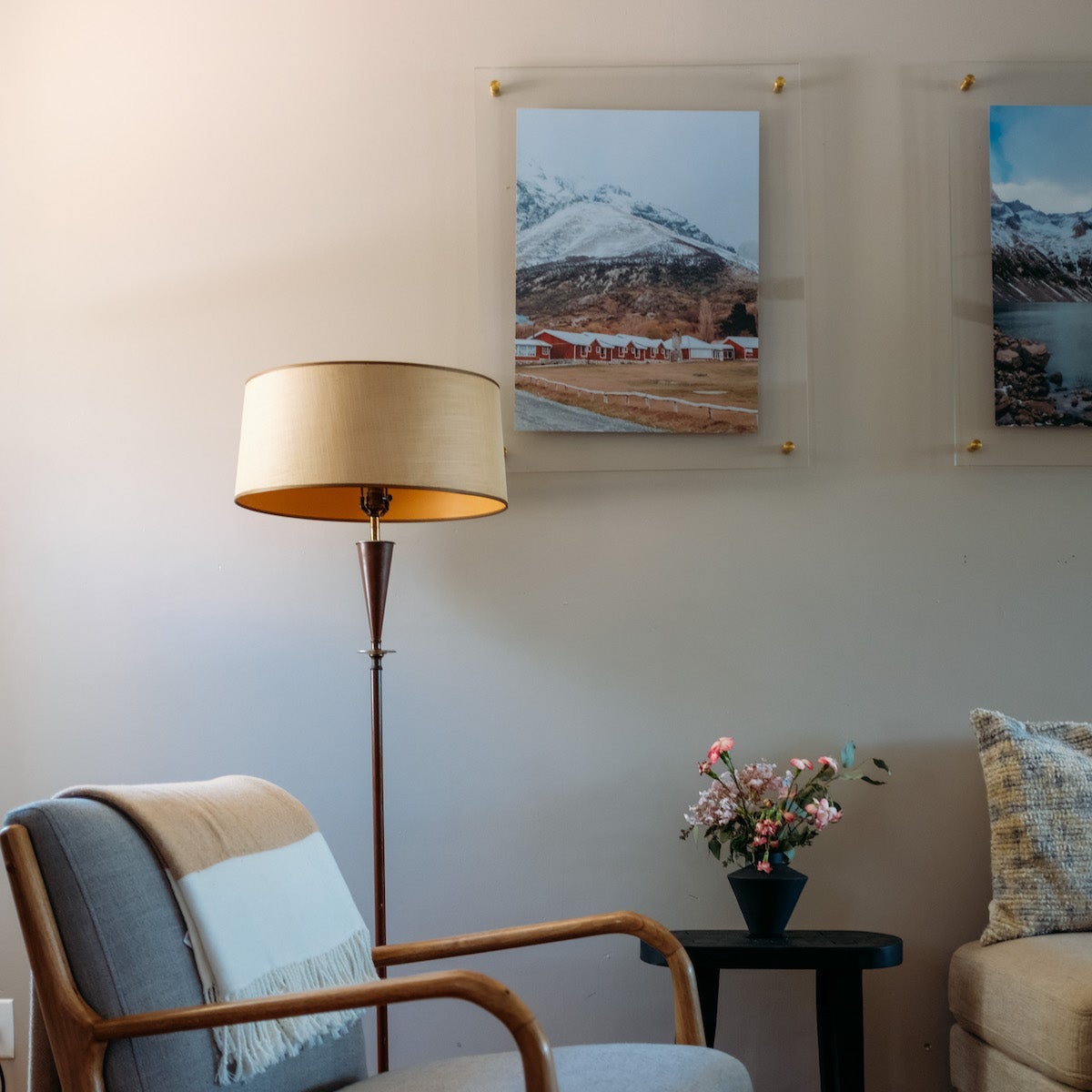 Frame with a mountain photo on the wall next to a lamp and accent chair.
