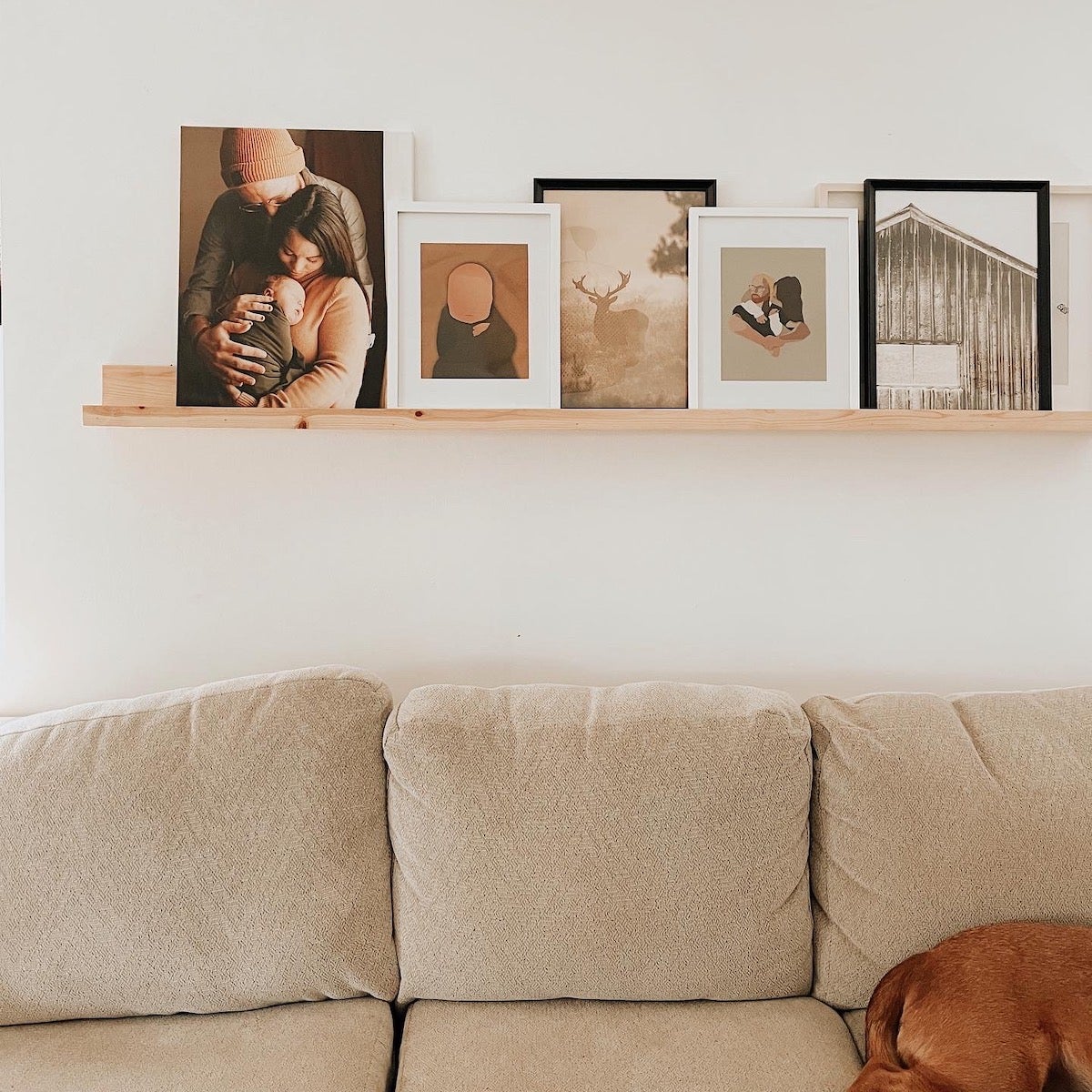 Photos and frames displayed above a couch along a wooden ledge.