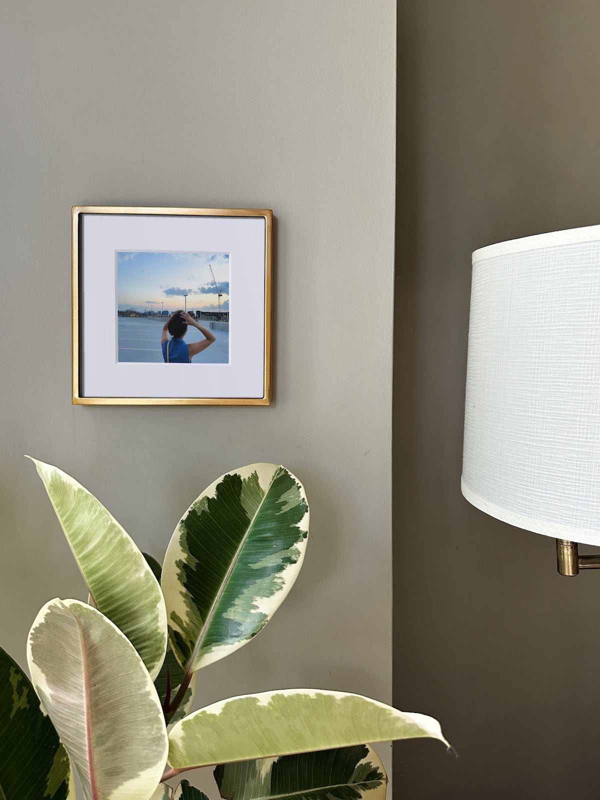 Artifact Uprising Metal Tabletop Frame in Brass finish hanging in corner of wall next to sconce and plant