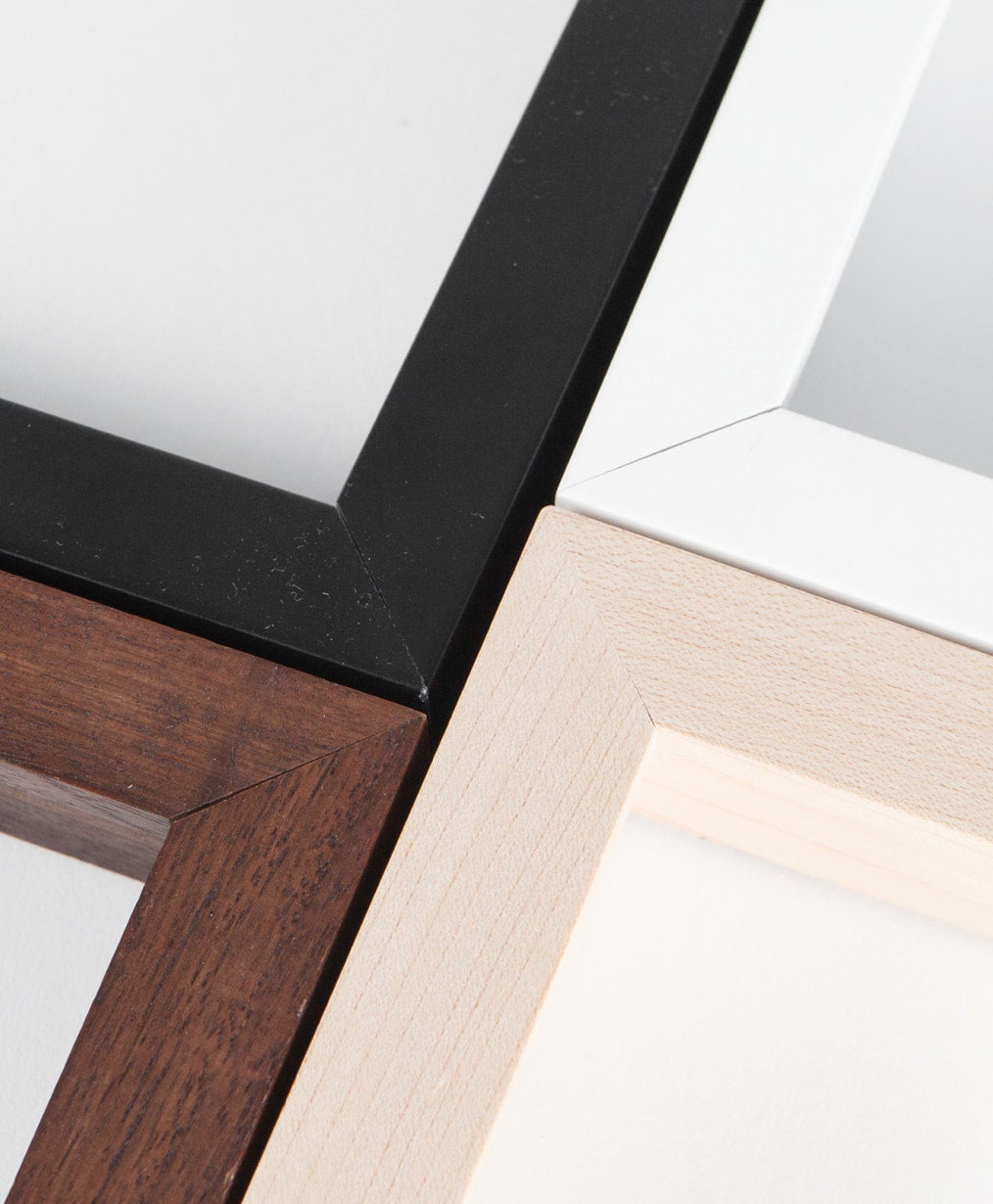 Close up corner shot of four wood gallery frames in black, white, walnut, and birch