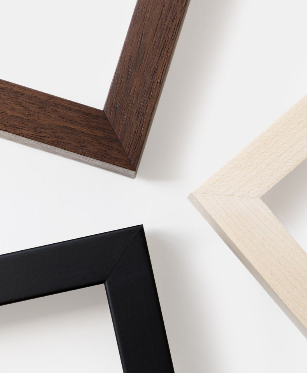 Close up corner shot of three wood deep-set frames in black, walnut, and birch