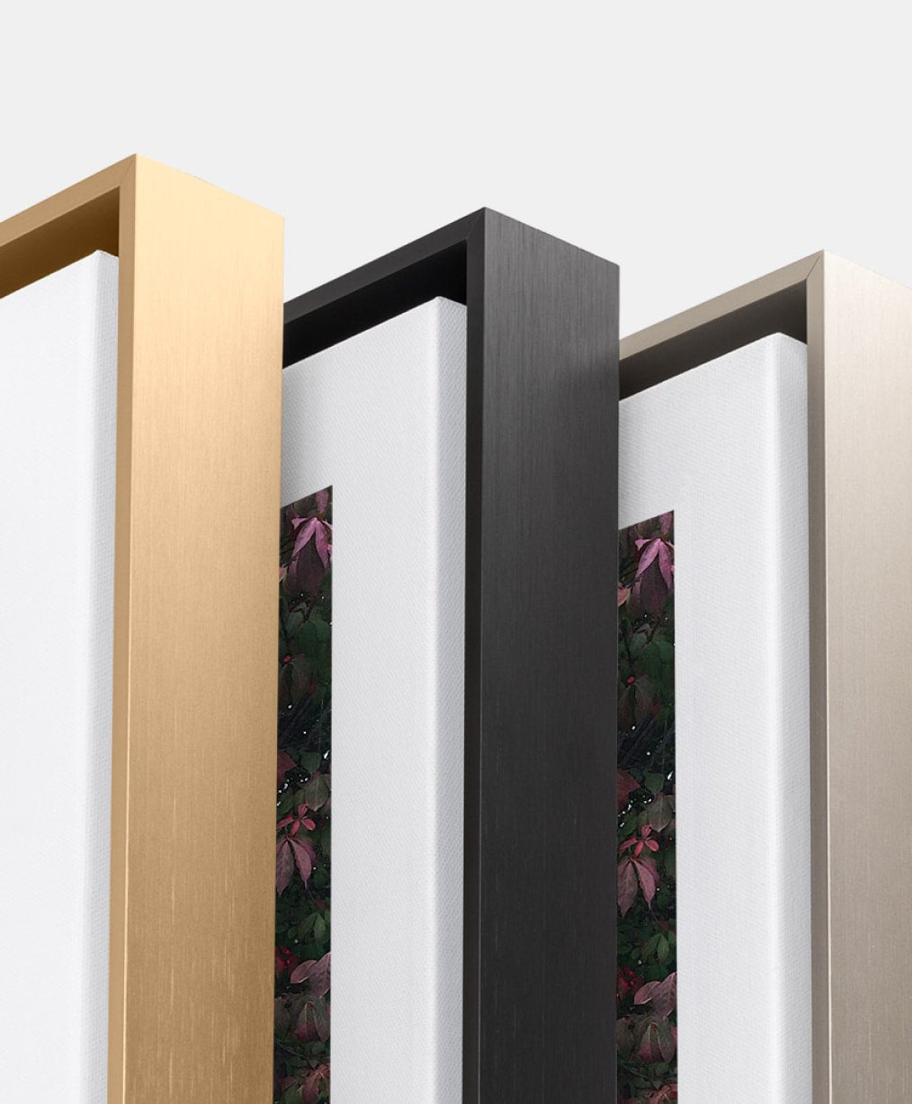 Close up corner shot of three Framed Canvas Prints in brass, black, and silver.