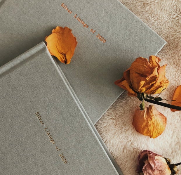 Two smoke gray Everyday Photo Books with rose petals on a sheepskin rug