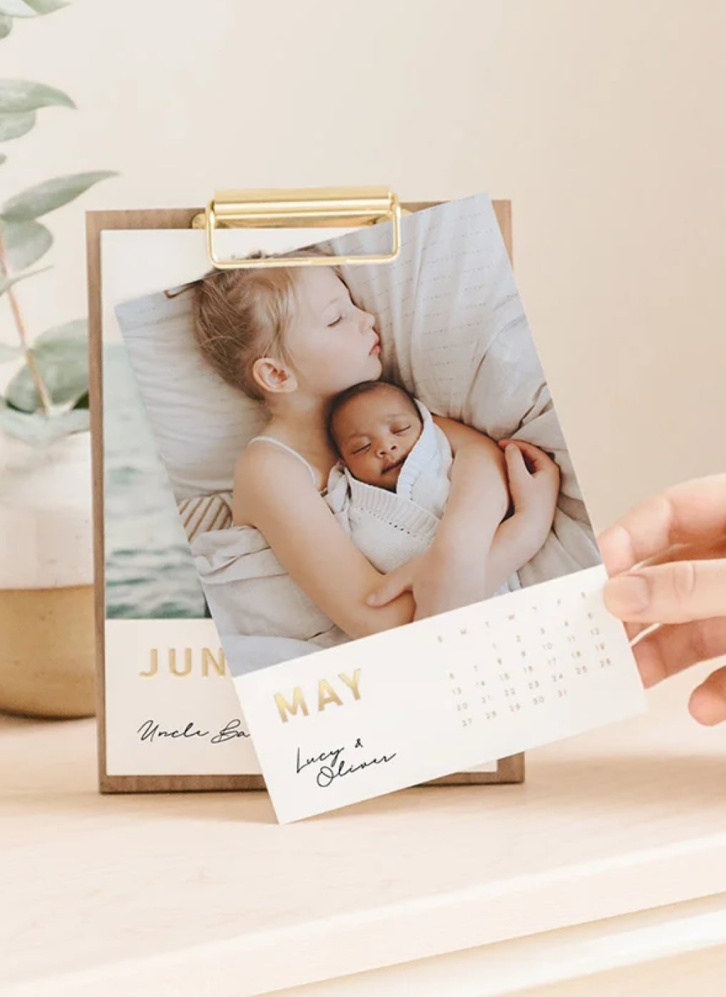 Walnut desktop calendar showing the month May with a photo of a little girl and baby brother hugging