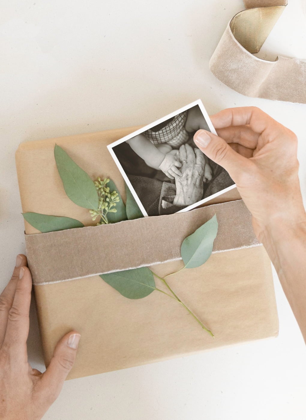 Kraft wrapped present with delicate leaf, ribbon, and everyday photo print