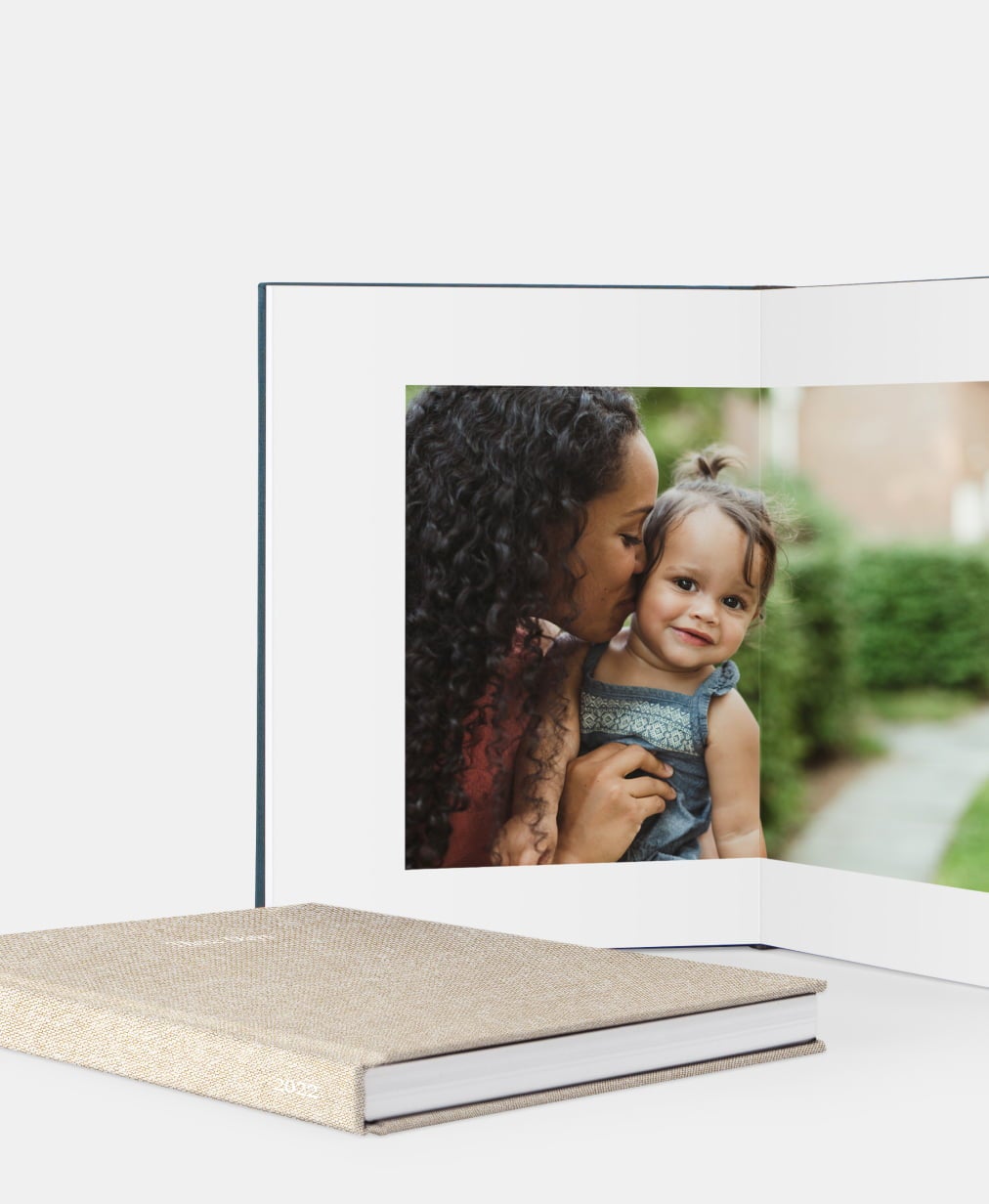Open oatmeal color layflat photo book with picture of mom and baby