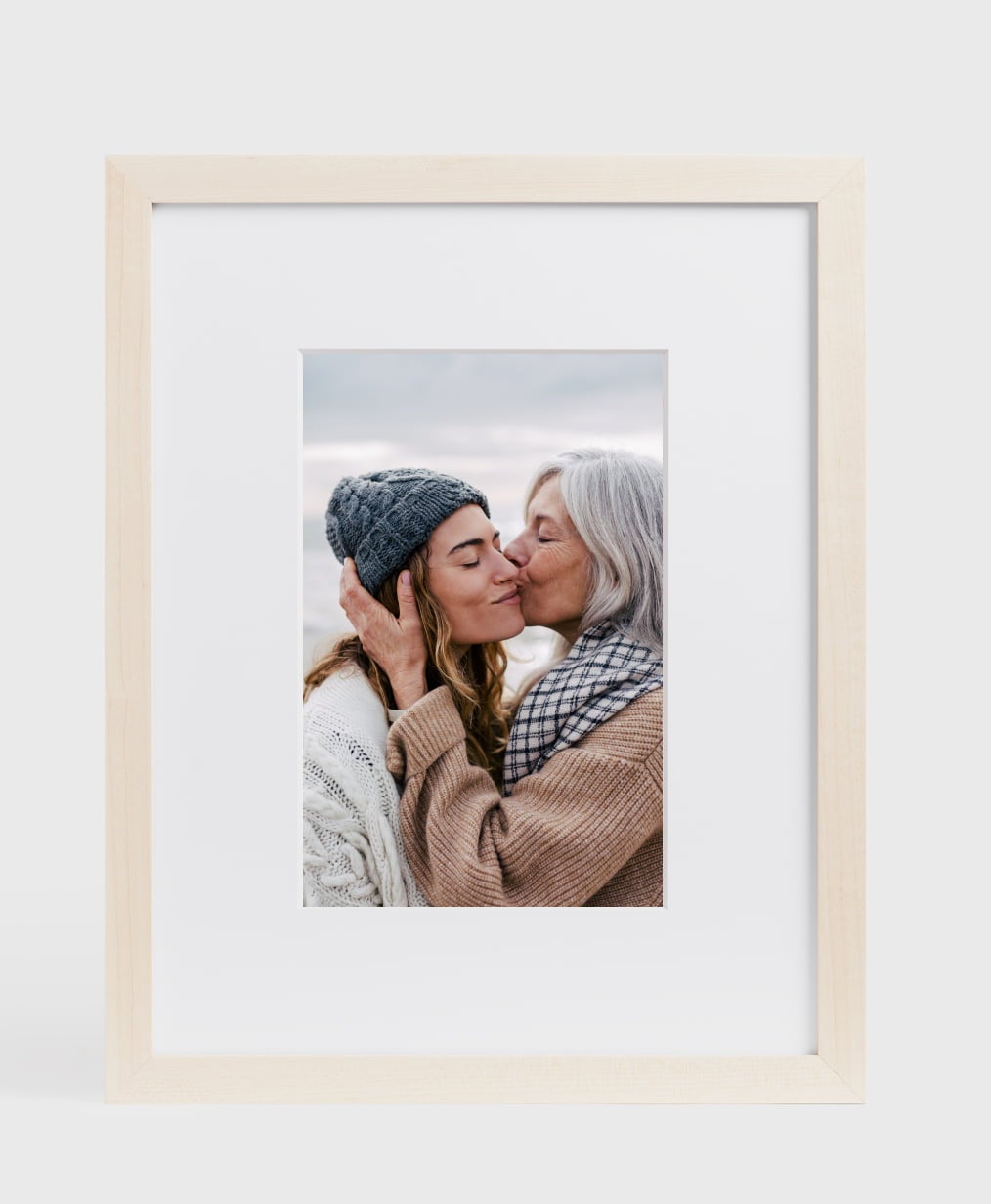 One maple finish gallery frame showing a picture of an older mom kissing her adult daughter on the cheek