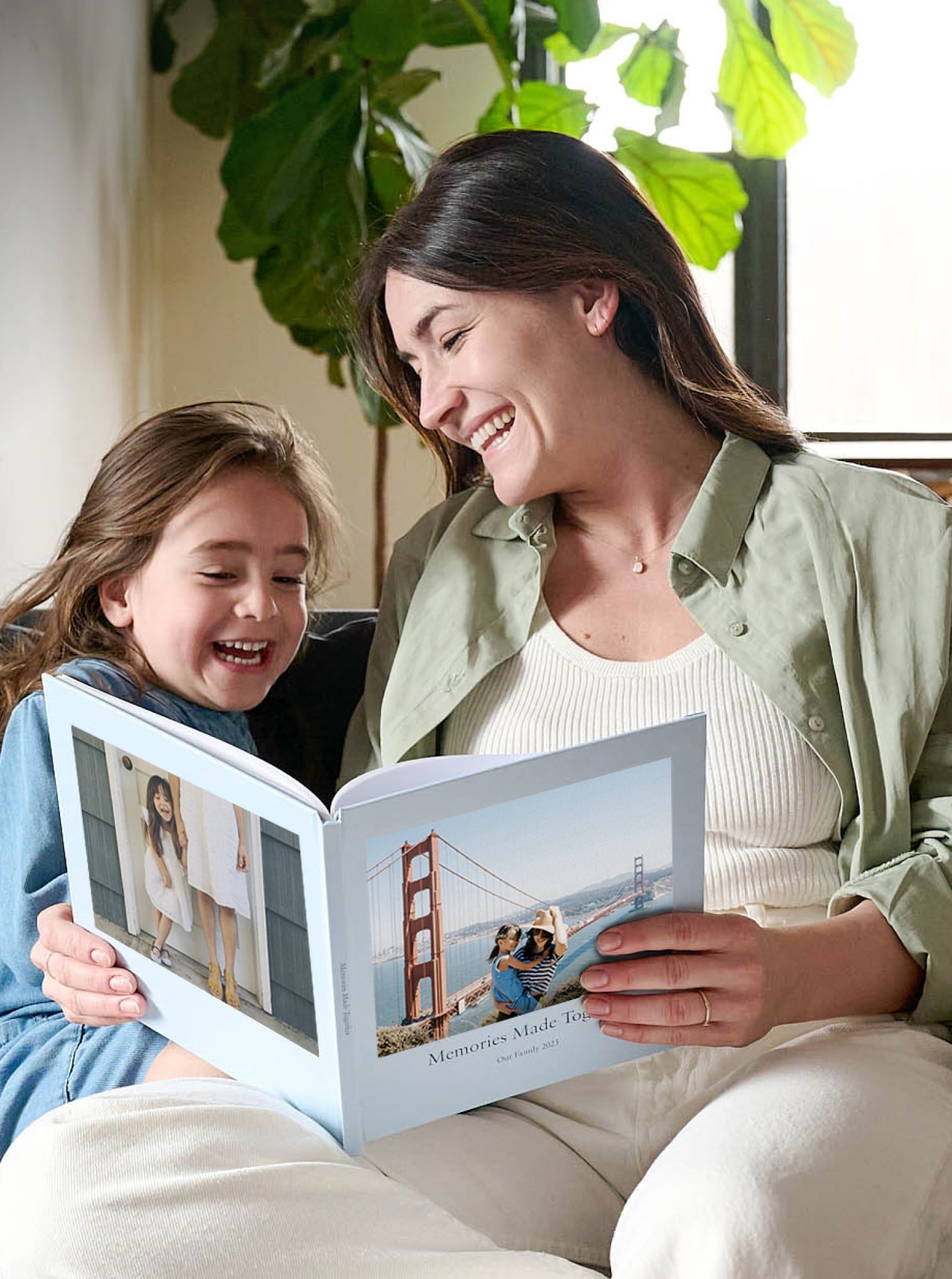 A mom and young daughter looking at a custom photo book and laughing