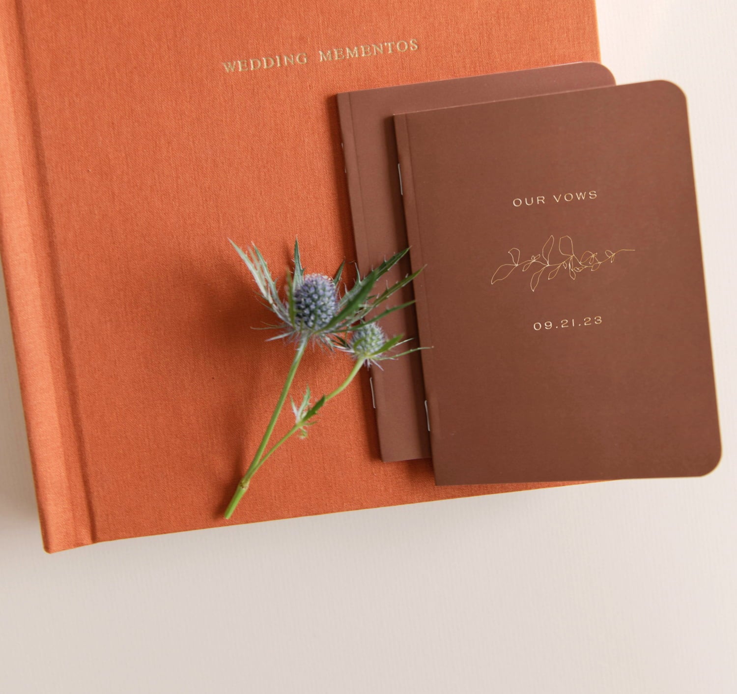 Closed Vow Book showcase the Our Vows cover stacked on top of terracotta Wedding Layflat Album