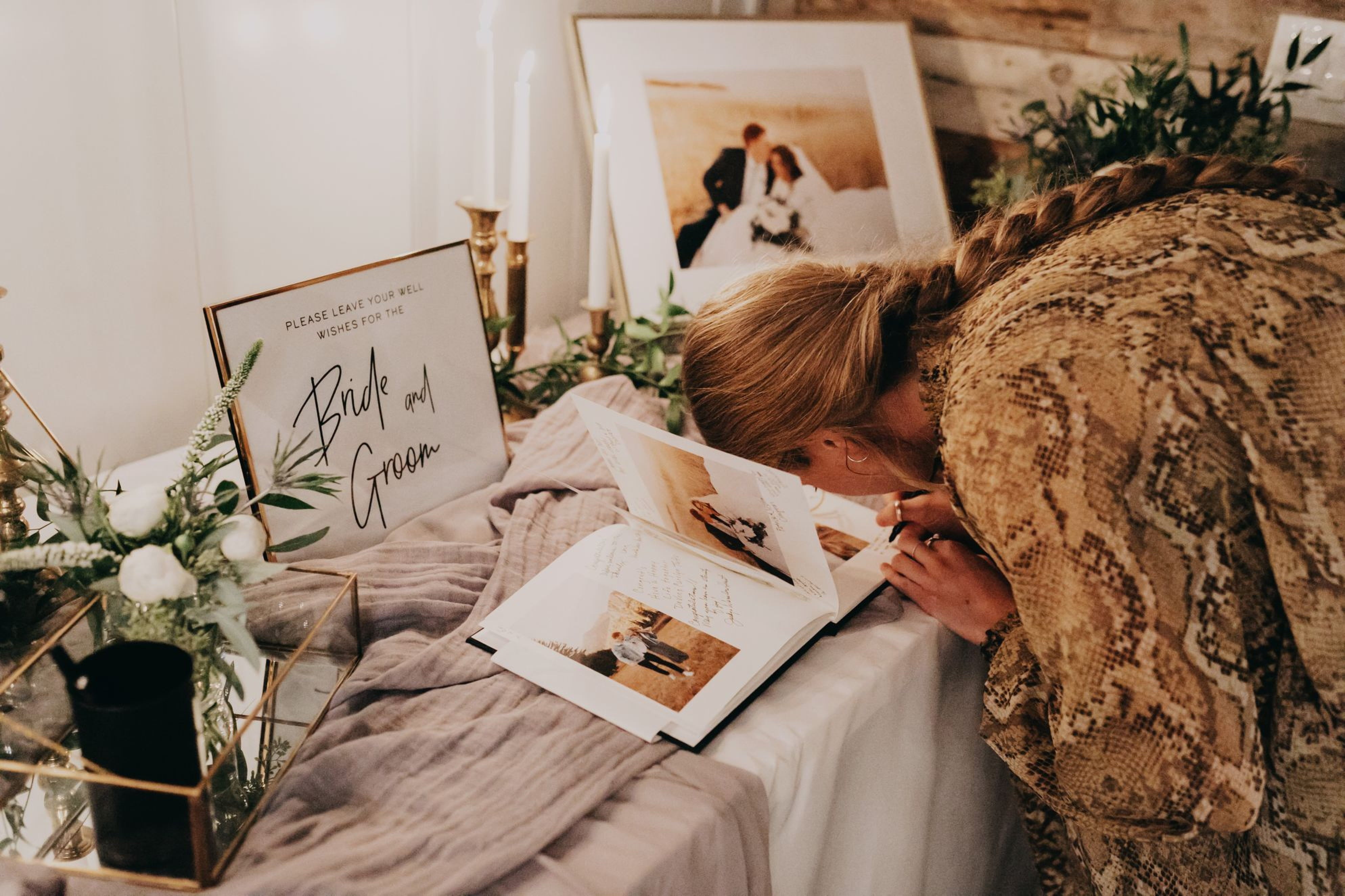 Woman signing Wedding Guest Book that features unique page image layouts and room for custom sentimental notes to be written