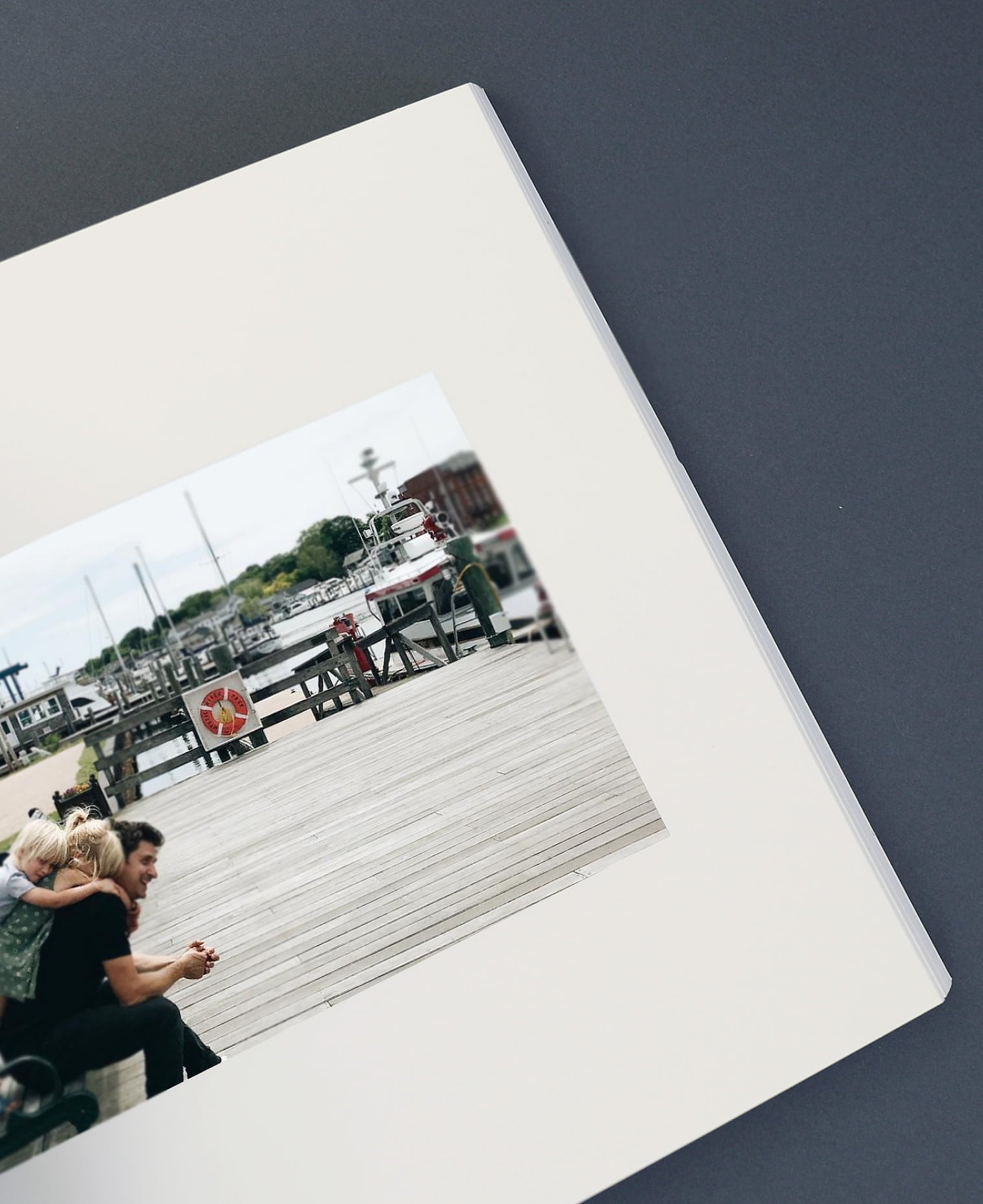 Open Softcover Photo Book featuring unique photo layout showcasing a photo of father sitting with two children leaning on his back