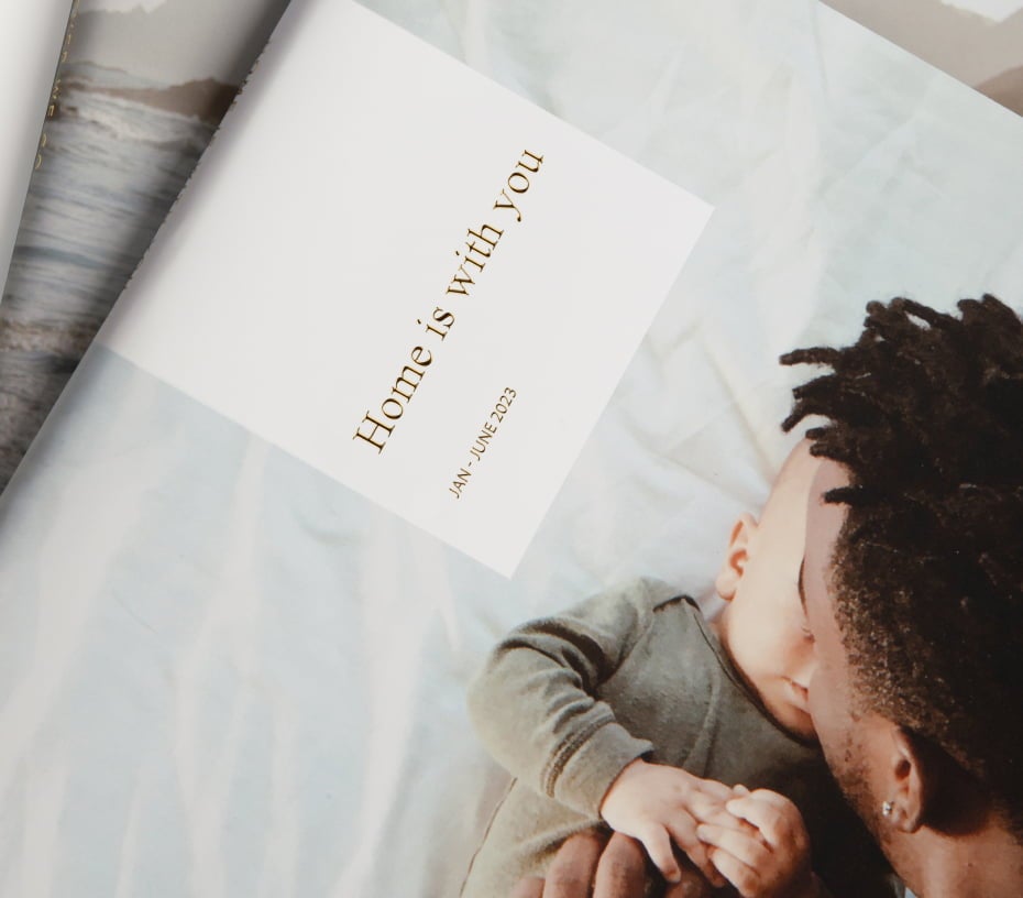 Hardcover Photo Album showcasing gold foil text that reads, “Home is with you Jan - June 2023” Featuring father cuddling baby