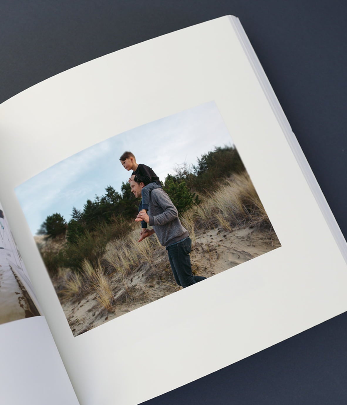 Softcover photo book showcasing horizontal image layout and photo of father with child on his shoulders