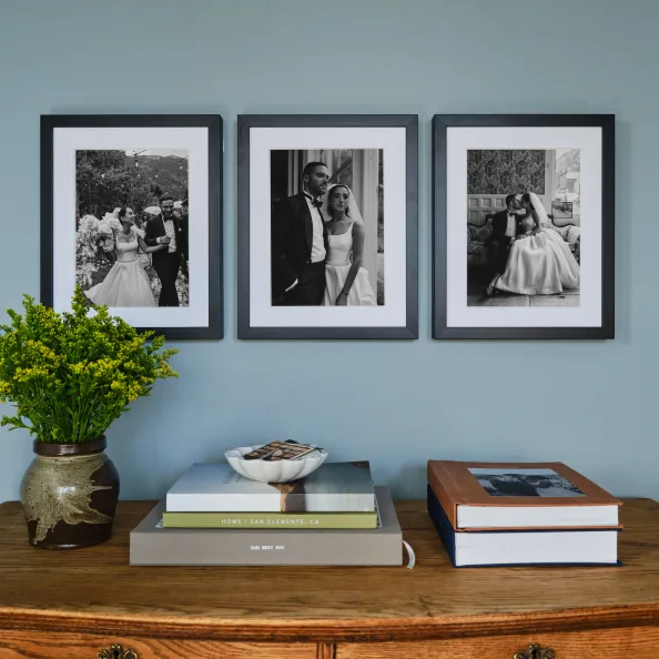 Three framed wedding photos above a console table