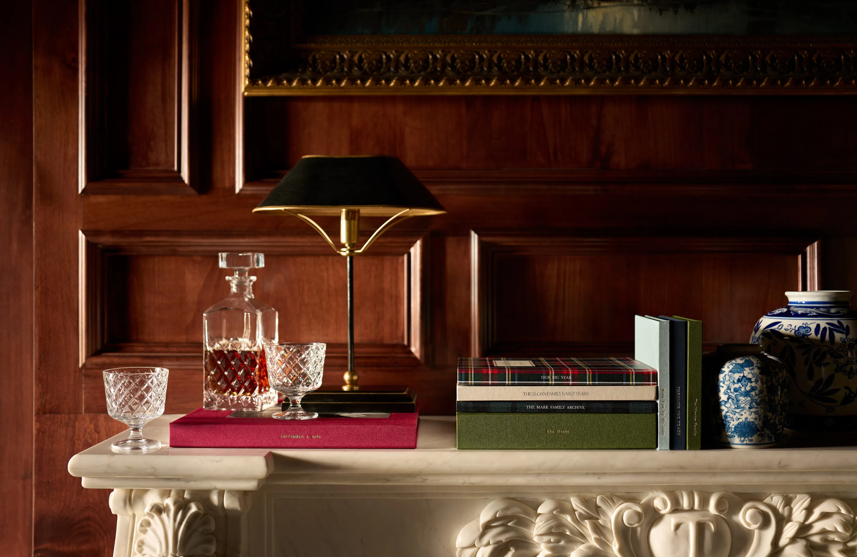 Heirloom photo books stacked on a marble mantel in a wood-panelled holiday room