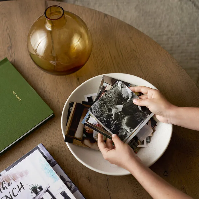 Hands holding Everyday Photo Prints over a ceramic bowl