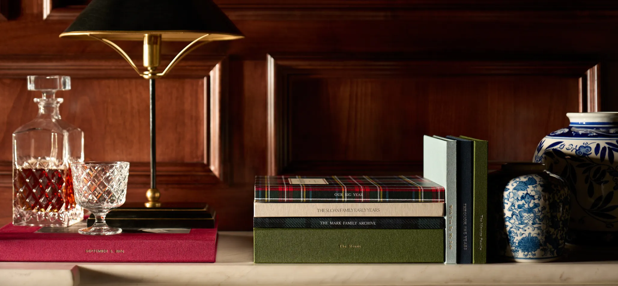 Heirloom photo books on a marble mantel in a wood-paneled holiday room