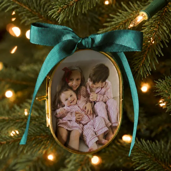 Vintage family photo ornament tied with a green ribbon on a Christmas tree