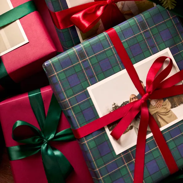 Holiday gifts wrapped in plaid paper, photo prints, and colorful ribbons