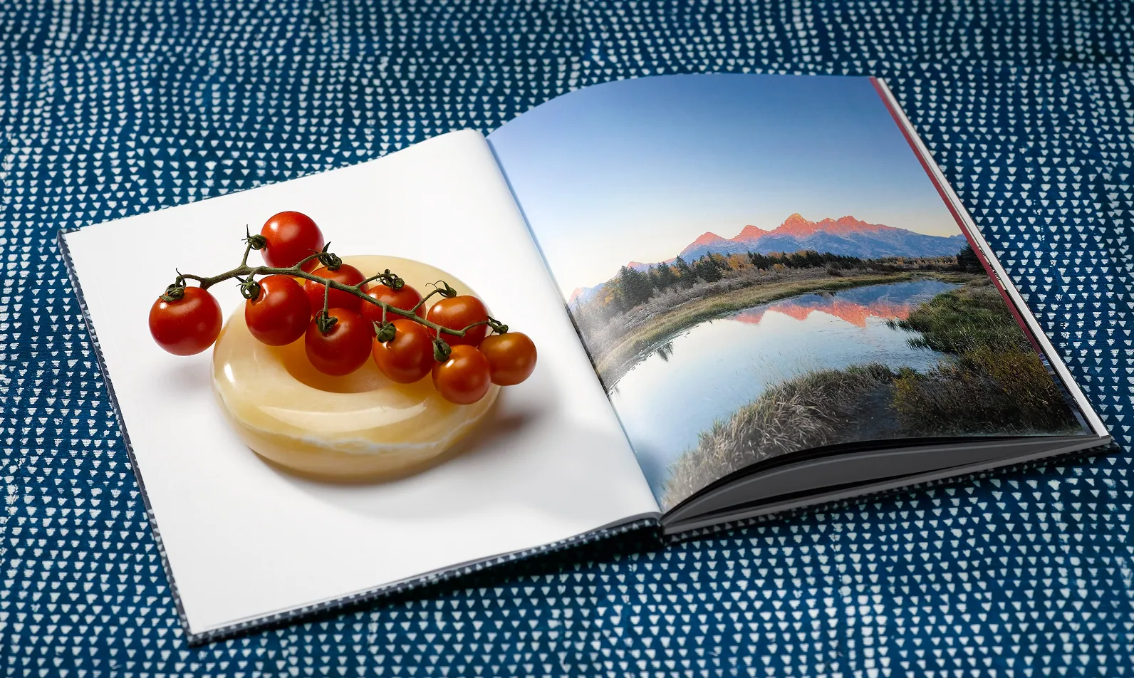 Open photo book with food and mountain photographs on indigo fabric