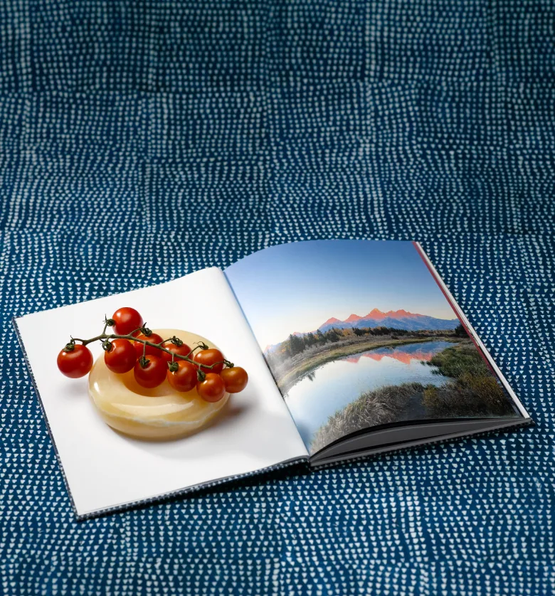 Open photo book with food and mountain photographs on indigo fabric