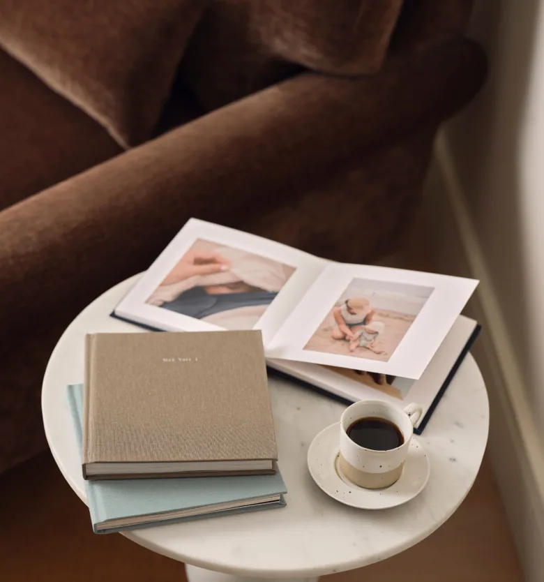 Photo books and coffee on a table beside a brown armchair