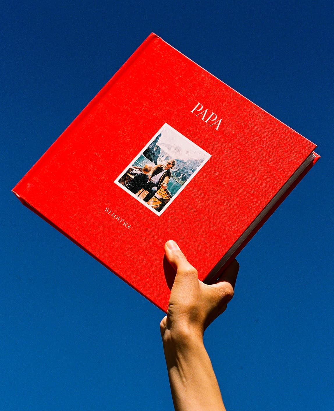 Red photo book held against a blue background