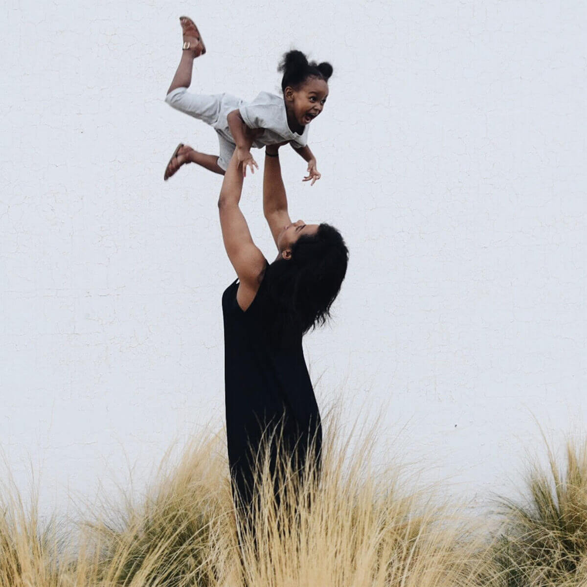 Mom tossing young daughter up in the air and catching her